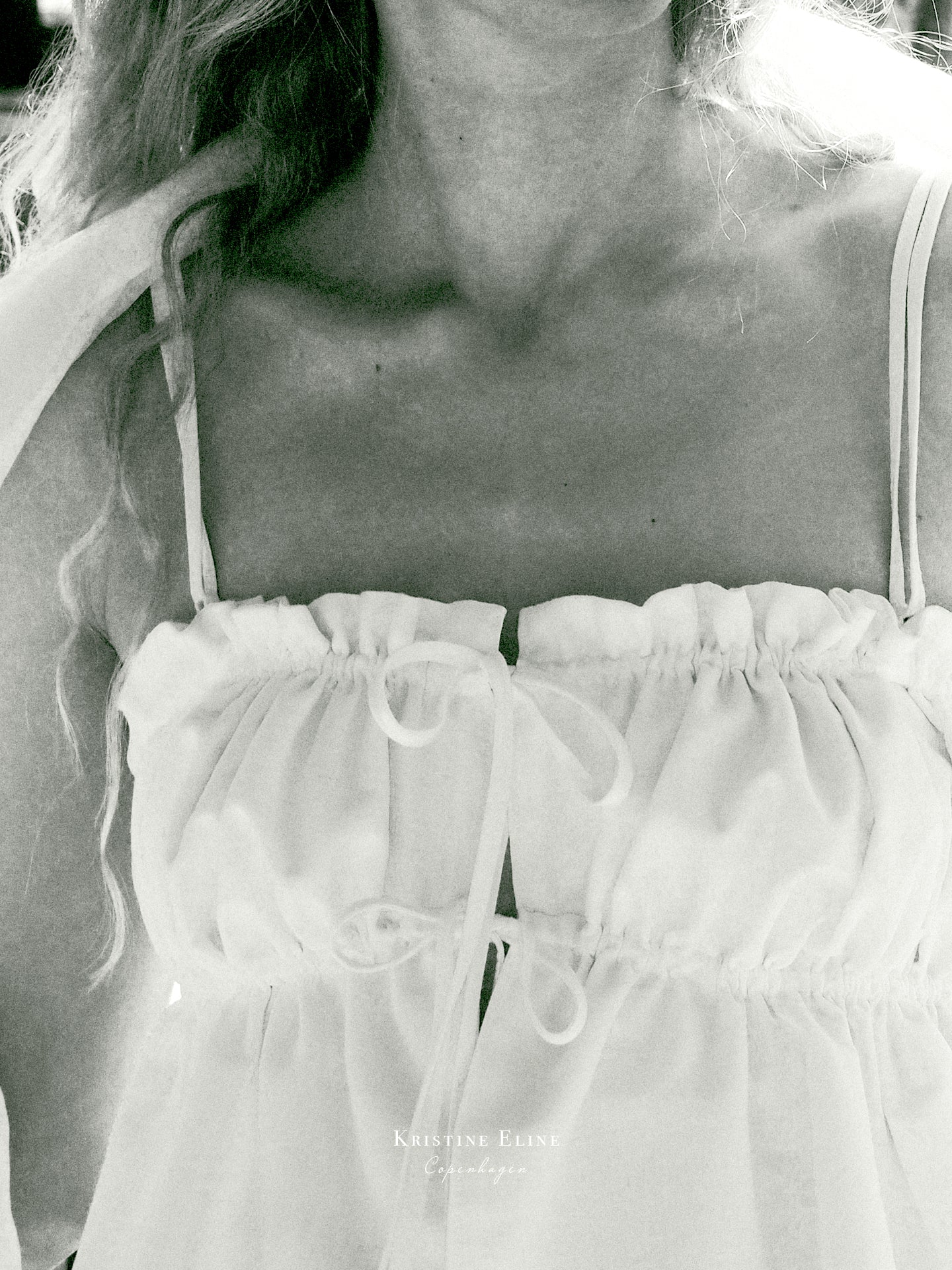 Close-up of a person wearing a white top with thin straps.