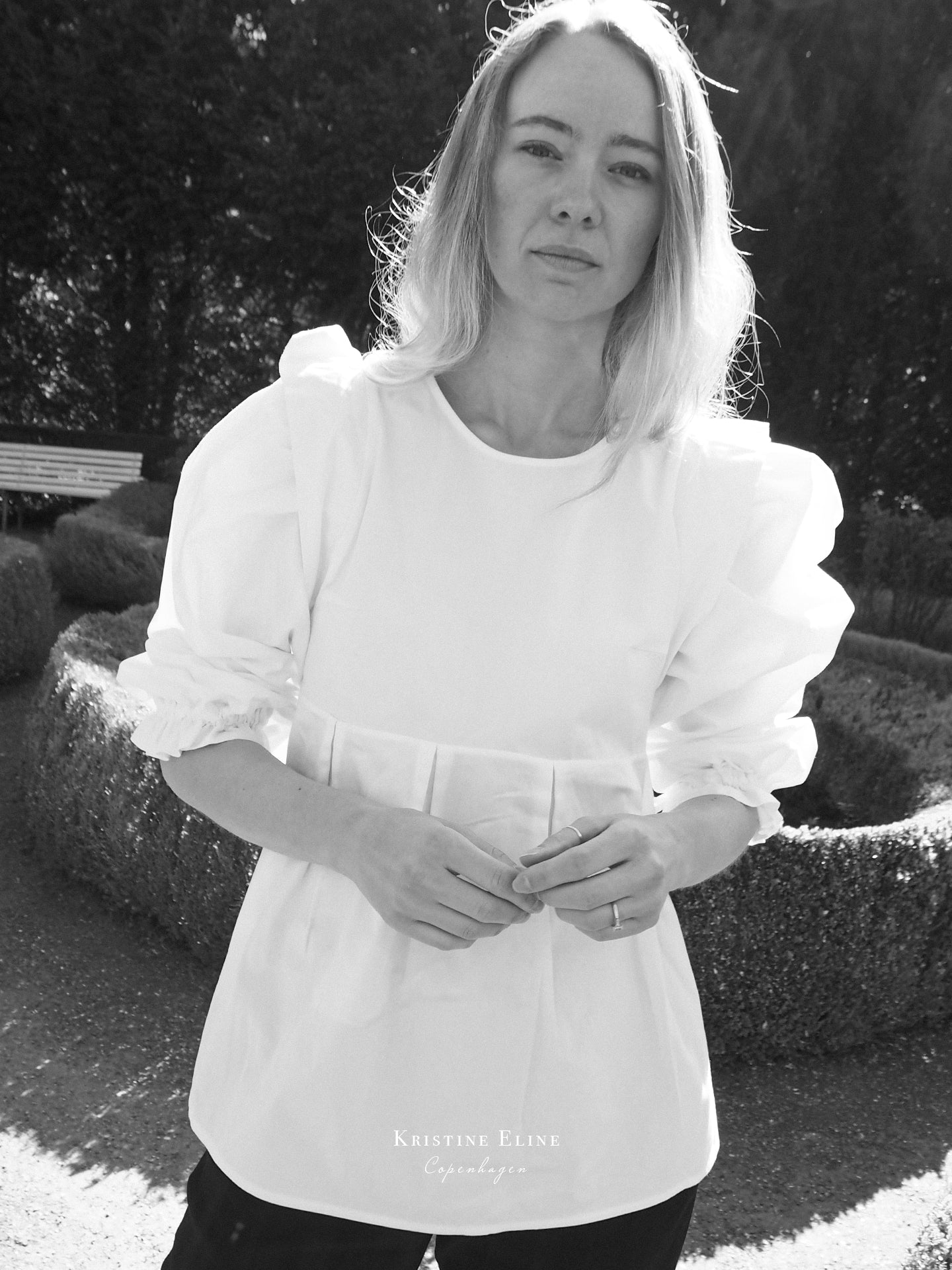 Girl wearing a white blouse with puffed sleeves in an outdoor setting in black and white