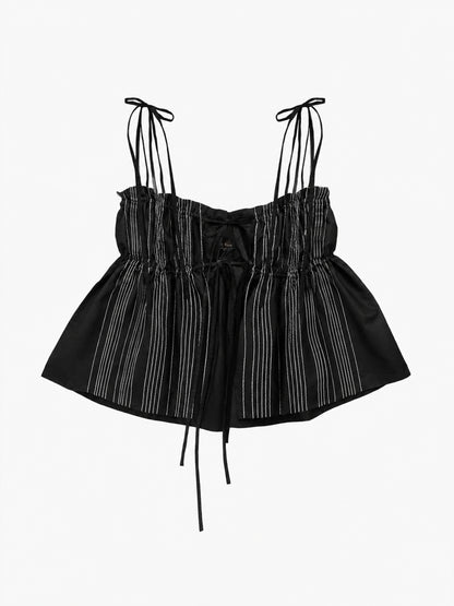 A black ruffled top with thin shoulder ties, a gathered ruffled bodice, and vertical white chain stitches, shown against a plain light grey background.