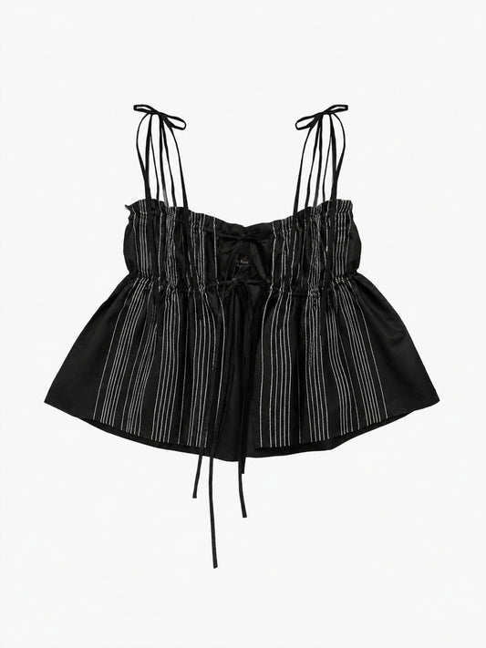 A black ruffled top with thin shoulder ties, a gathered ruffled bodice, and vertical white chain stitches, shown against a plain light grey background.