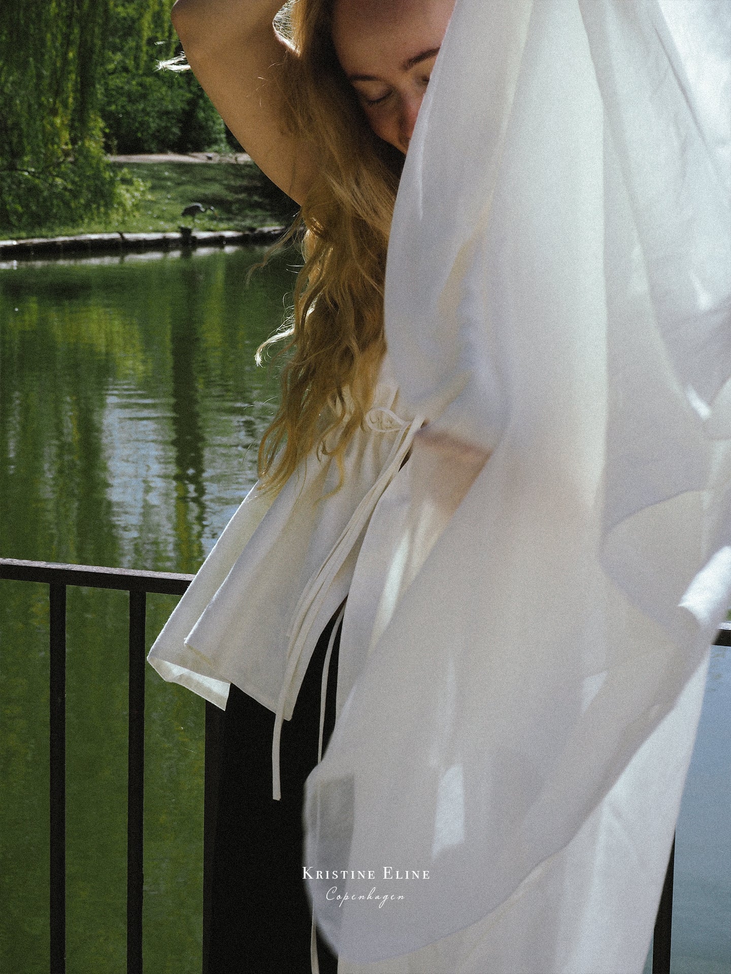 Person wearing a ivory top with a blurred background of a lake and trees