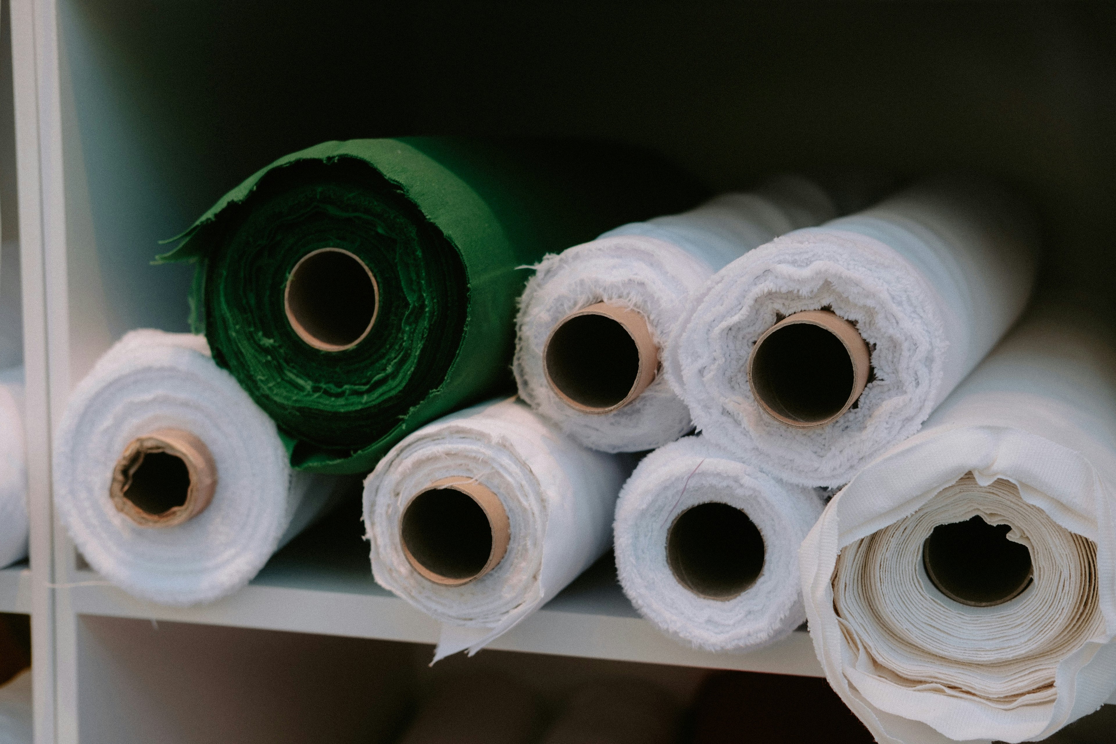 Rolls of green and white fabric on a shelf